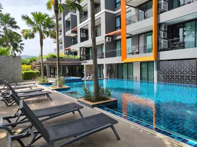 a swimming pool with chaise lounge chairs in front of a building at Nai Harn beach - Studio room on 2 floor at ReLife The Windy in Rawai Beach