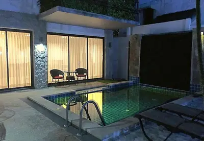 a swimming pool with a table and chairs next to a building at Exquisite 3BR Private Pool Villa: Prime Location in Kamala Beach