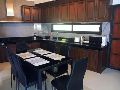 a kitchen with a table with chairs and a microwave at Exquisite 3BR Private Pool Villa: Prime Location in Kamala Beach