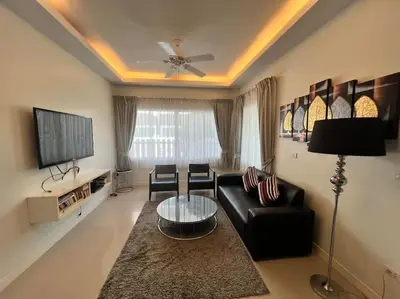 a living room with a black couch and a tv at Stunning 4-BR House with Inviting Swimming Pool in Kamala Beach