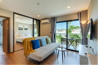 a living room with a couch and a bed and a balcony at The Title V Rawai by Beringela in Phuket Town