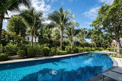 a swimming pool with palm trees and a building at The Title V Rawai by Beringela in Phuket Town
