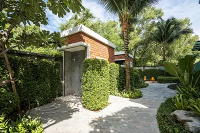 a garden with a brick wall and a walkway at The Title V Rawai by Beringela in Phuket Town