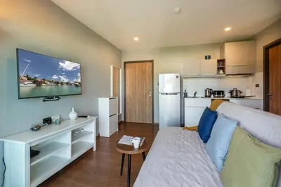 a living room with a couch and a kitchen at The Title V Rawai by Beringela in Phuket Town