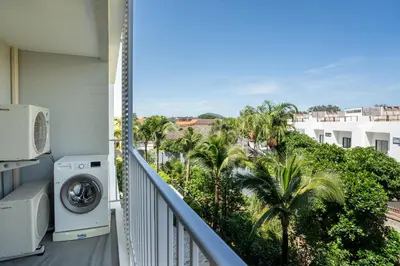 a balcony with a washing machine and palm trees at The Title V Rawai by Beringela in Phuket Town