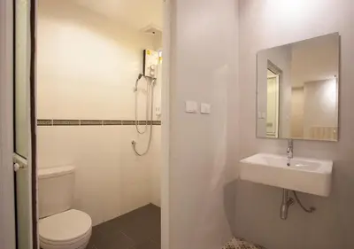 a white bathroom with a toilet and a sink at Nature Pine Phuket เนเชอร์ไพน์ภูเก็ต in Rawai Beach