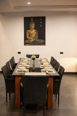 a dining room with a table with chairs and a statue at Phuket Superior Sunrise Sea View Private Pool Villa in Kata Beach