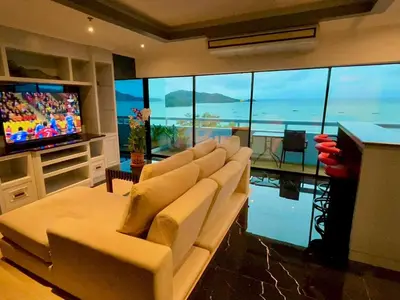 a living room with white chairs and a television at Patong Tower Holiday Rentals in Patong Beach