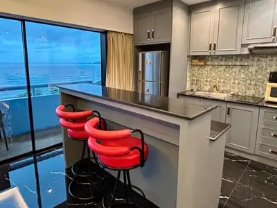 a kitchen with red stools at a counter with a view at Patong Tower Holiday Rentals in Patong Beach
