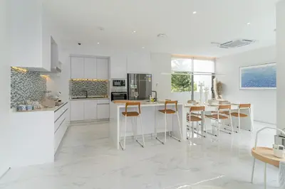 a kitchen with white cabinets and bar stools at Exquisite Pool Residence A19: Aesthetics and Luxury Combined in Bang Tao Beach