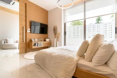 a bedroom with a bed with white pillows and a tv at Exquisite Pool Residence A19: Aesthetics and Luxury Combined in Bang Tao Beach