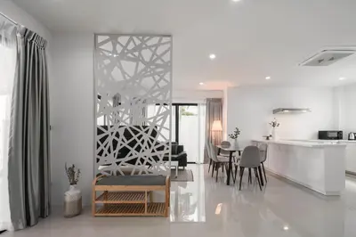 a living room with white walls and a table and chairs at Chao Wilai Residence I Naiyang Beach I HKT Airport in Nai Yang Beach