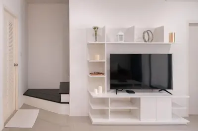 a living room with a tv and a white wall at Chao Wilai Residence I Naiyang Beach I HKT Airport in Nai Yang Beach