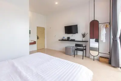 a white bedroom with a bed and a chair at The Elements Boutique House in Phuket Town