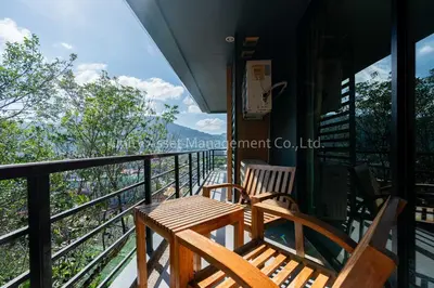 two wooden chairs sitting on the balcony of a house at The Unity and The Bliss Patong Residence in Patong Beach