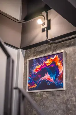 a painting hanging on a wall with a light at Black Panther Hostel in Phuket Town