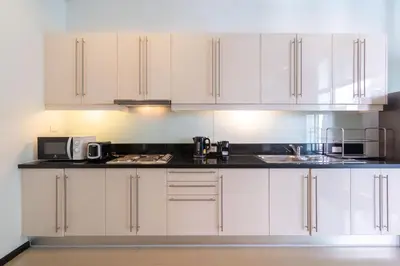a kitchen with white cabinets and a black counter top at Tropical Garden Villa - Oxygen Bangtao Beach in Bang Tao Beach