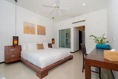 a bedroom with a bed and a desk and a ceiling fan at Tropical Garden Villa - Oxygen Bangtao Beach in Bang Tao Beach
