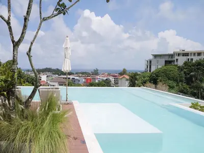 a large swimming pool with an umbrella and a building at Karon beach apartment & sea view pool in Karon Beach