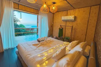 a bedroom with a large bed and a large window at Greenheart Garden View Camp Phuket in Kata Beach