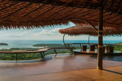a resort with benches and a view of the ocean at Greenheart Garden View Camp Phuket in Kata Beach