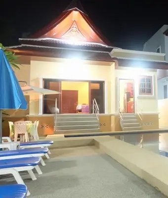 a house with chairs and a swimming pool at night at Majestic Villas Phuket in Rawai Beach