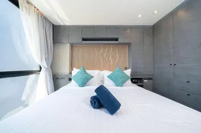 a bedroom with a large white bed with blue pillows at Modern Tropical Kamala Beach in Phuket Town