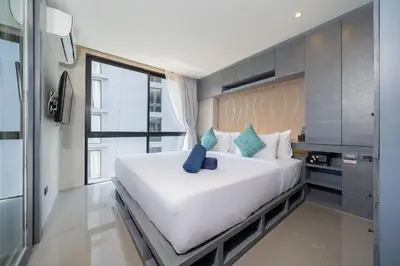 a bedroom with a large white bed with blue pillows at Modern Tropical Kamala Beach in Phuket Town