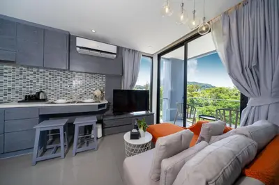 a living room with a couch and a kitchen at Modern Tropical Kamala Beach in Phuket Town