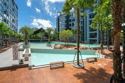 a swimming pool with benches and palm trees in a city at Modern Tropical Kamala Beach in Phuket Town