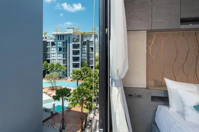 a bedroom with a view of a pool and a building at Modern Tropical Kamala Beach in Phuket Town