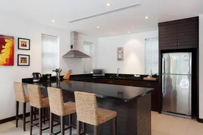 a kitchen with a bar with chairs and a refrigerator at The Residence Villa 203 in Bang Tao Beach