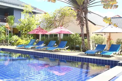 a pool with chairs and umbrellas next to a building at Blue Palm Kata Resort in Kata Beach