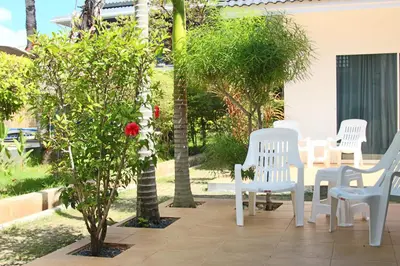 a patio with white chairs and a tree with a red rose at Blue Palm Kata Resort in Kata Beach