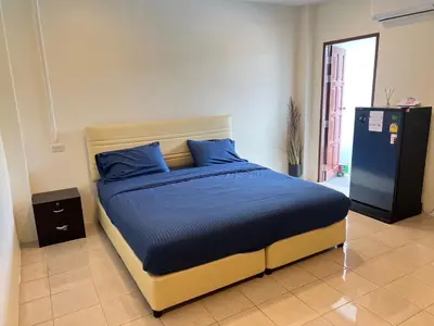 a bedroom with a bed with blue sheets and a refrigerator at AB House in Kathu