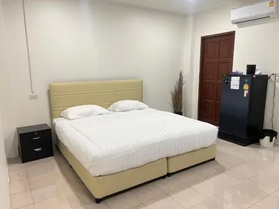 a bedroom with a bed and a refrigerator at AB House in Kathu