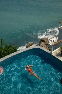 a person in a swimming pool next to the ocean at Villa Nevaeh - Ocean Front Private Villa Kamala Beach in Phuket Town