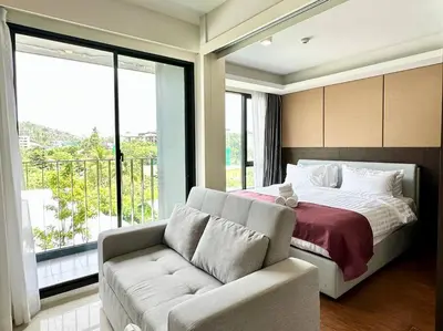 a bedroom with a bed and a couch and a window at Aristo Resort Surin Beach M18 in Phuket Town