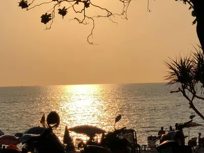 a group of people on a beach with the sun reflecting on the water at Aristo Resort Surin Beach M18 in Phuket Town