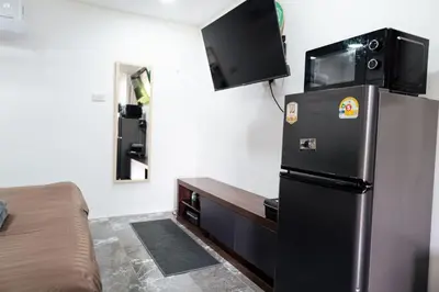 a room with a refrigerator with a tv on the wall at Apollo Hotel Chalong in Ban Suan