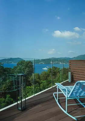 a blue chair sitting on a deck with a view of the water at Bluepoint SeaView Retreat Patong in Patong Beach
