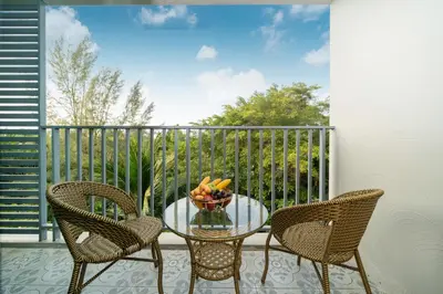 a glass table with two chairs and a bowl of fruit on a balcony at The Title Residencies Nai Yang - 1 Bedroom Apartment in Nai Yang Beach