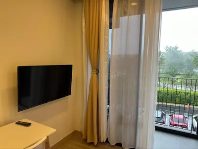 a room with a television and a window with a balcony at Apartments in Skypark Laguna Bang Tao in Bang Tao Beach