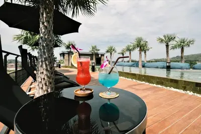 two cocktails sitting on a table next to a pool at Kamala Beach P73 Exclusive Junior Suite in Kamala Beach