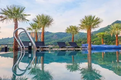 a swimming pool with palm trees in the background at Kamala Beach P73 Exclusive Junior Suite in Kamala Beach