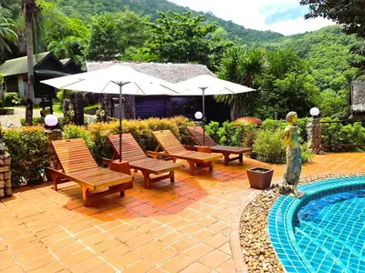 a patio with chairs and an umbrella next to a pool at Boomerang Village Resort Kata in Kata Beach
