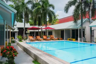 a swimming pool with chairs and umbrellas next to a building at Maiiam Bungalows Kata Beach in Kata Beach