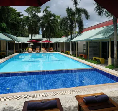 a large swimming pool with chairs and umbrellas at Maiiam Bungalows Kata Beach in Kata Beach