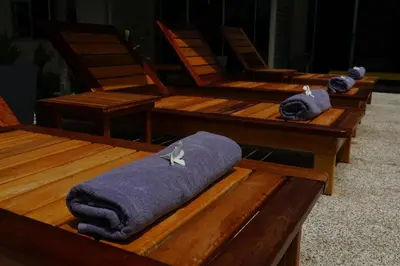 a row of wooden chairs with towels on them at Maiiam Bungalows Kata Beach in Kata Beach