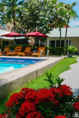 a pool with chairs and red flowers next to a resort at Maiiam Bungalows Kata Beach in Kata Beach